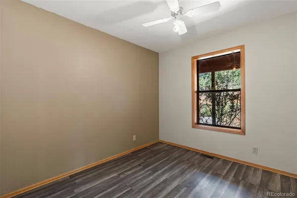 an empty room with wooden floor closet and windows