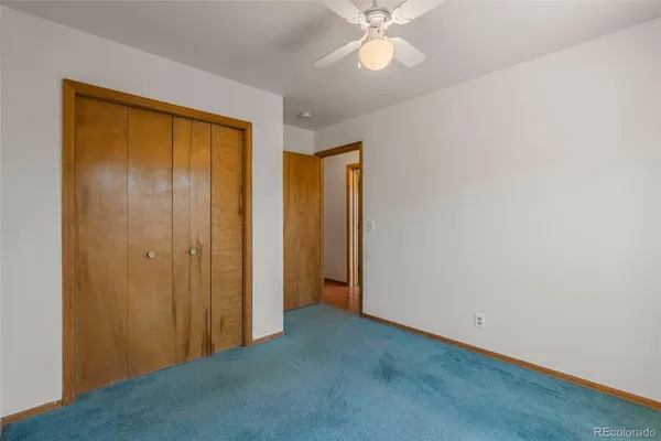 a view of an empty room with window and chandelier fan