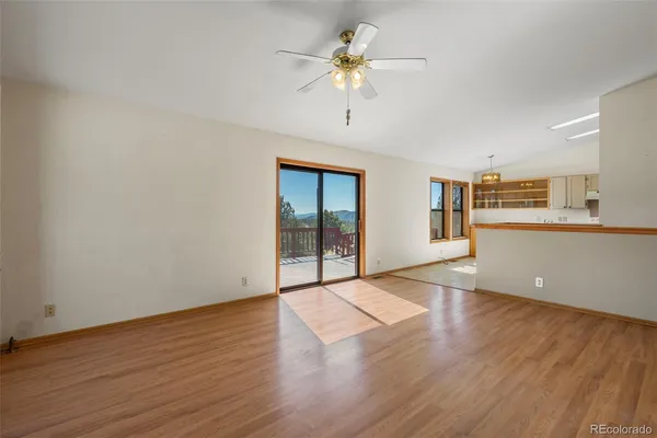 a view of an empty room with a window and wooden floor