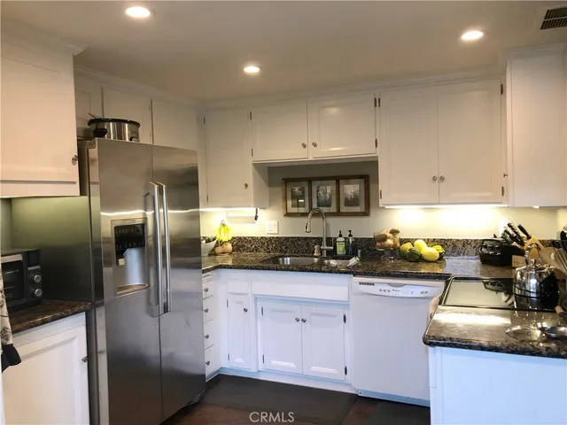 a kitchen with granite countertop a sink a counter space appliances and cabinets
