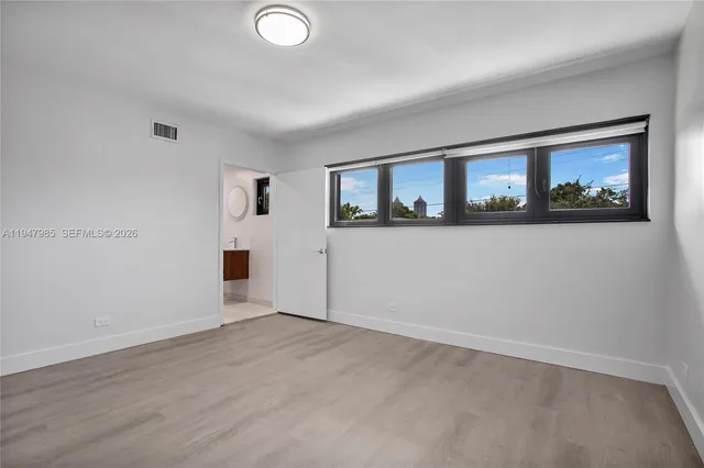 an empty room with windows and refrigerator