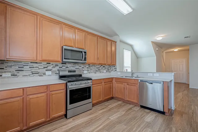a kitchen with granite countertop cabinets stainless steel appliances and wooden floor