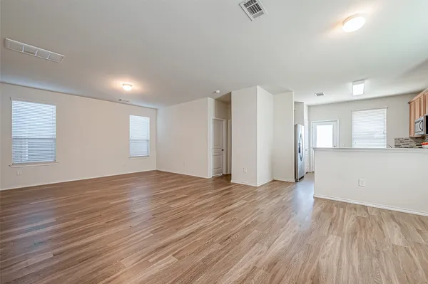 an empty room with wooden floor and windows