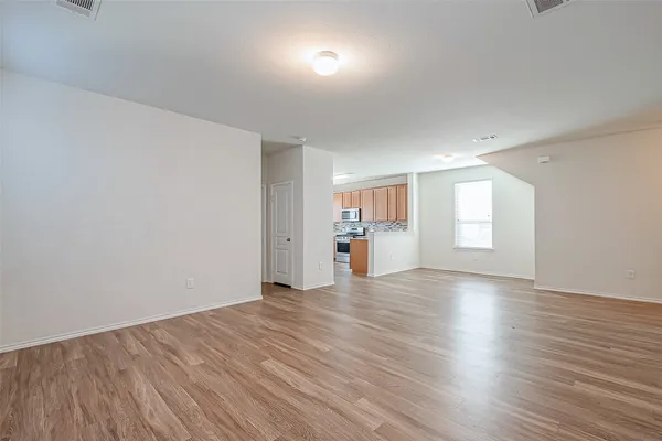 a view of empty room with wooden floor and windows