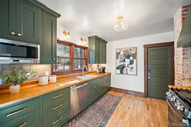 a large kitchen with stainless steel appliances wooden floor and a counter top space