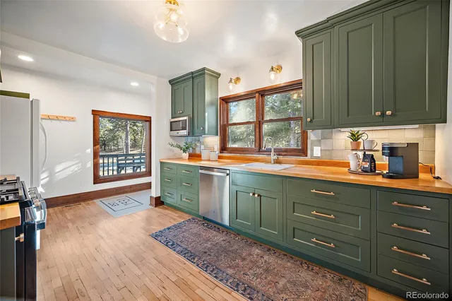 a kitchen with stainless steel appliances granite countertop a sink dishwasher a stove and a refrigerator with wooden floor