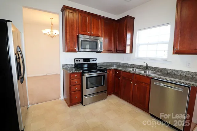 a kitchen with stainless steel appliances granite countertop a refrigerator stove and sink