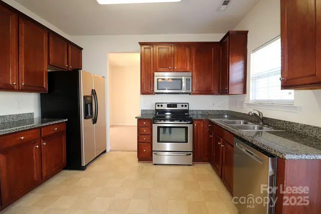 a kitchen with stainless steel appliances granite countertop a stove a refrigerator and a sink