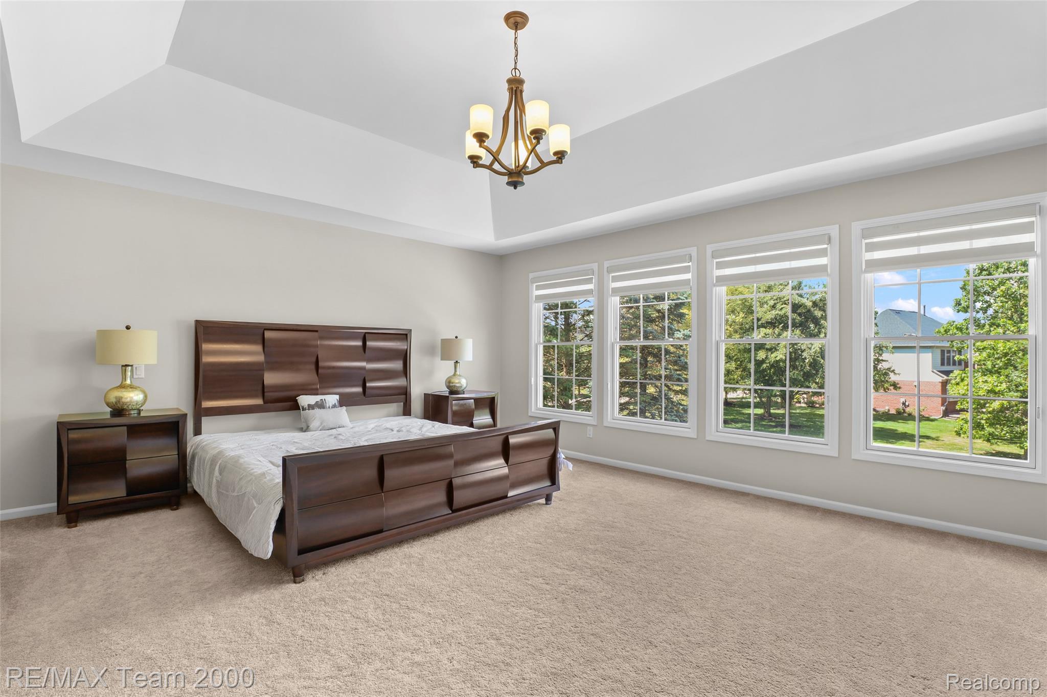 1248 Lasalle Road Canton, MI 48187 - Photo 52 of 67 Spacious bedroom featuring a tray ceiling with a central chandelier, light-toned carpeting, and a wall of four large windows