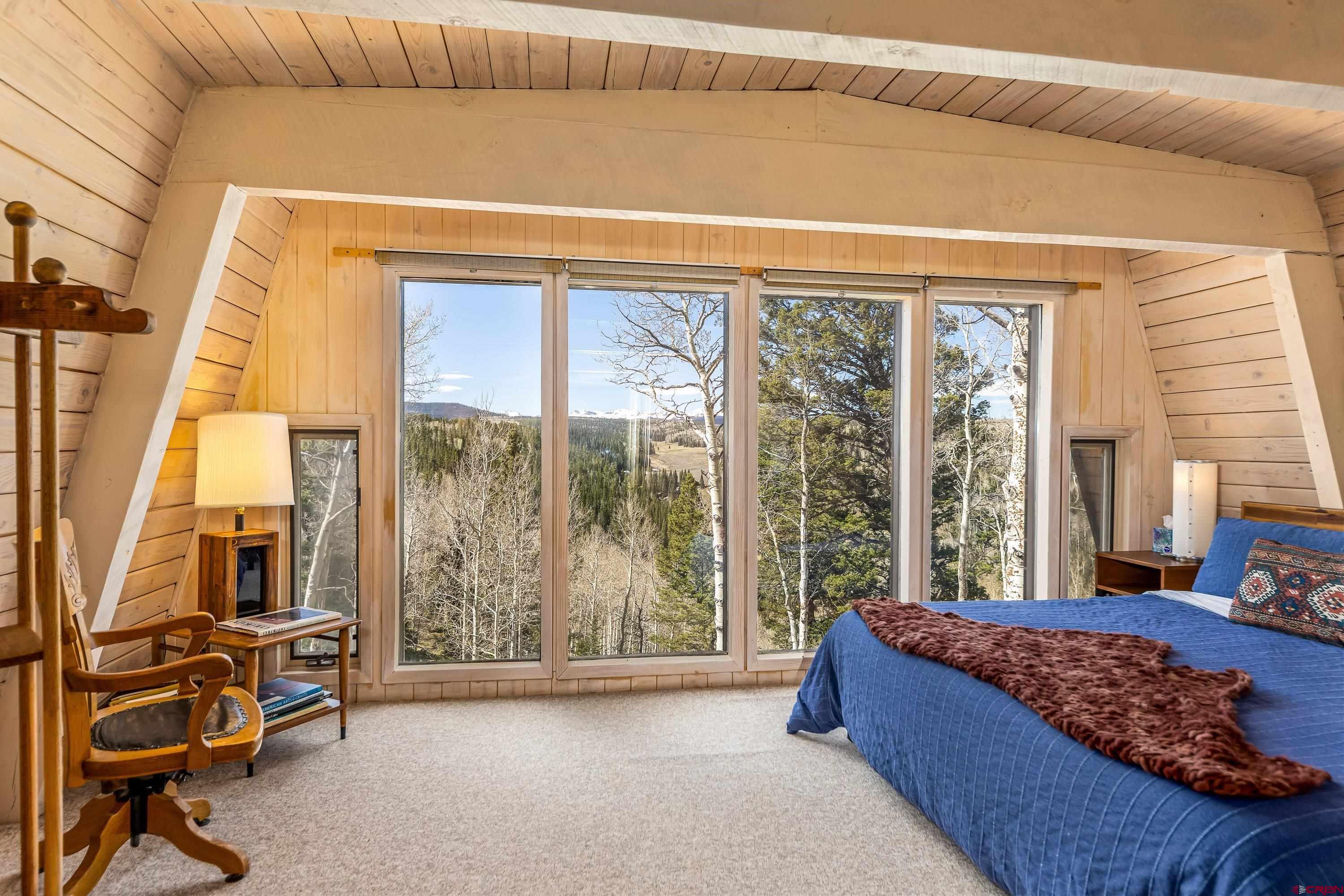 771 Spruce Road Cimarron, CO 81220 - Photo 18 of 34 a bedroom with a bed and large windows