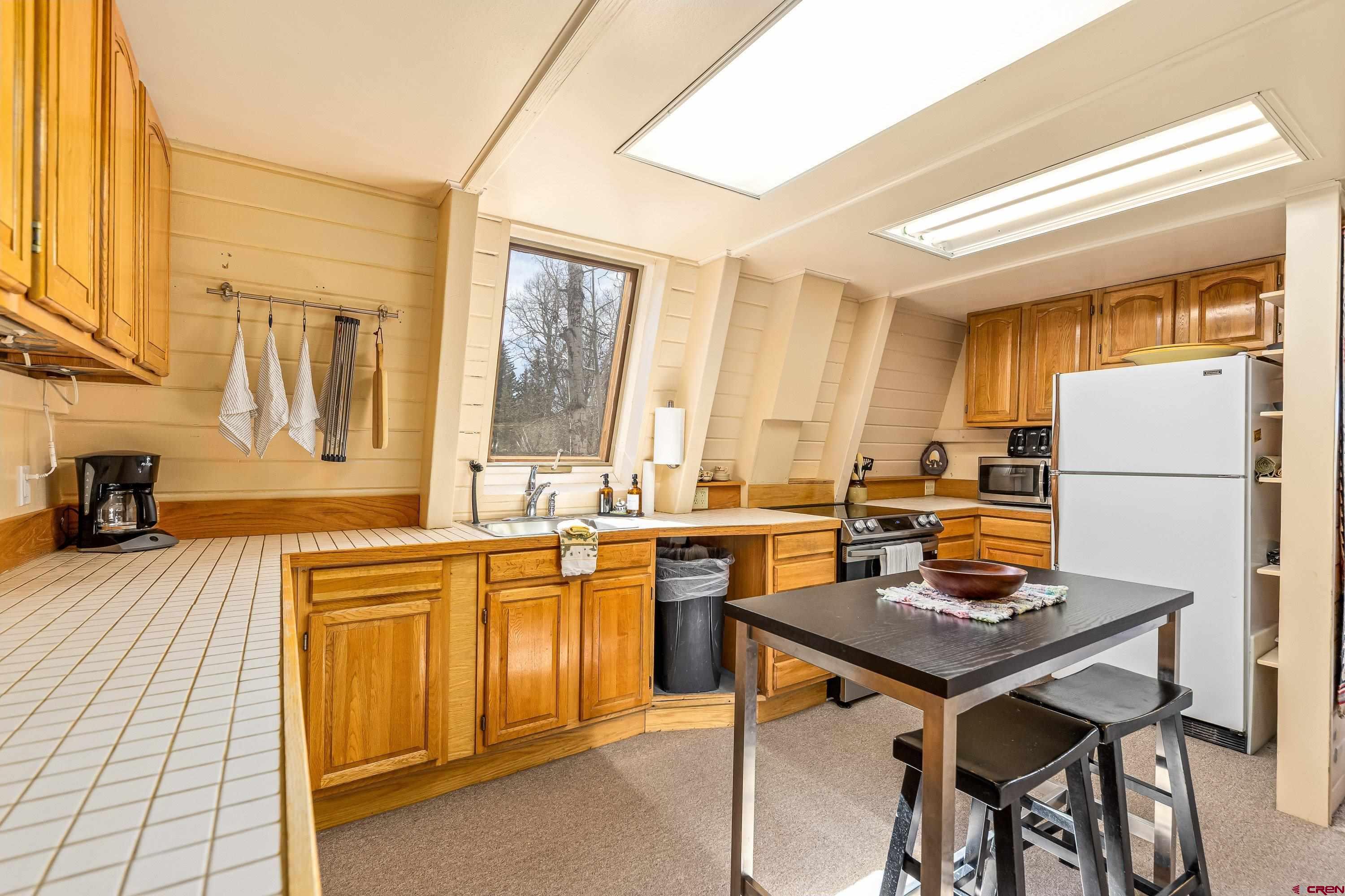 771 Spruce Road Cimarron, CO 81220 - Photo 9 of 34 a kitchen with a table chairs refrigerator and cabinets