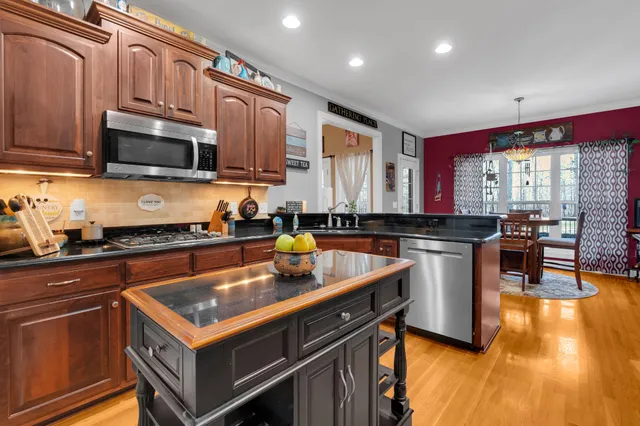 a kitchen with stainless steel appliances granite countertop a stove a sink dishwasher and cabinets with wooden floor