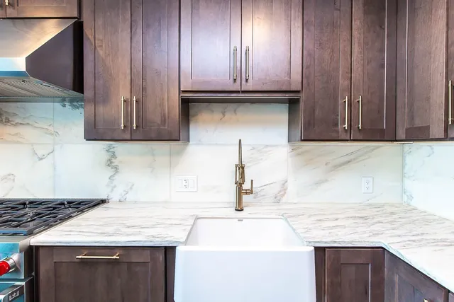 a kitchen with granite countertop a sink dishwasher stove and cabinets