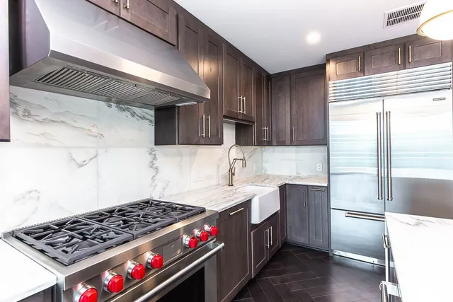 a kitchen with stainless steel appliances granite countertop a stove a sink dishwasher and cabinets with wooden floor