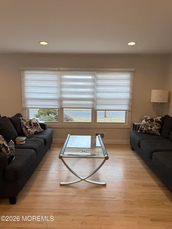 a living room with furniture a large window and a wooden floor