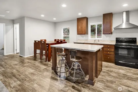 a kitchen with stainless steel appliances granite countertop a stove top oven a sink a dining table and chairs