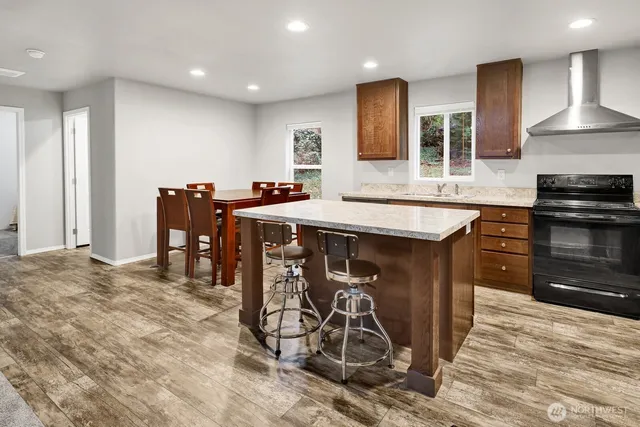 a kitchen with stainless steel appliances granite countertop a stove top oven a sink a dining table and chairs