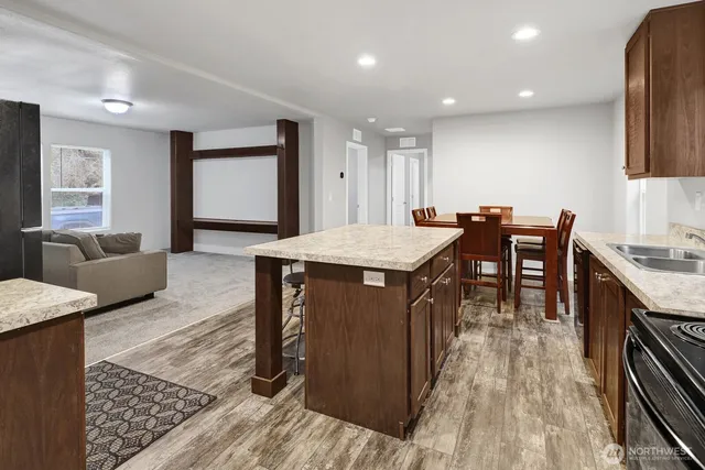 a living room with stainless steel appliances granite countertop furniture wooden floor and a kitchen view