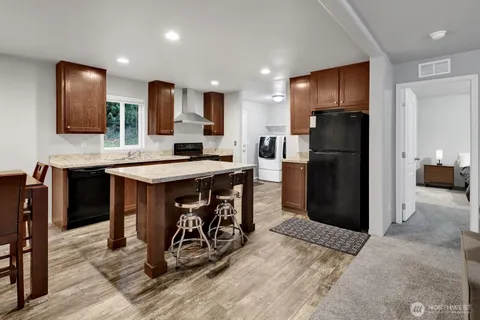 a kitchen with stainless steel appliances kitchen island granite countertop a refrigerator and a sink