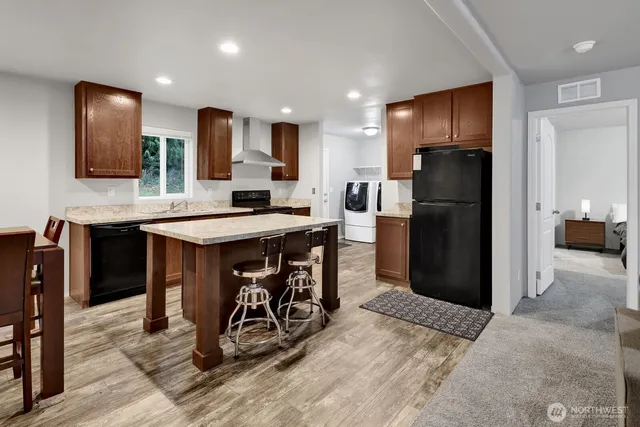 a kitchen with stainless steel appliances kitchen island granite countertop a refrigerator and a sink