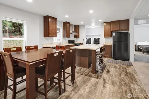 a kitchen with stainless steel appliances granite countertop a table chairs sink refrigerator and cabinets