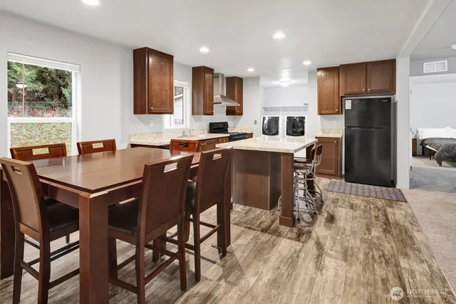 a kitchen with stainless steel appliances granite countertop a table chairs sink refrigerator and cabinets