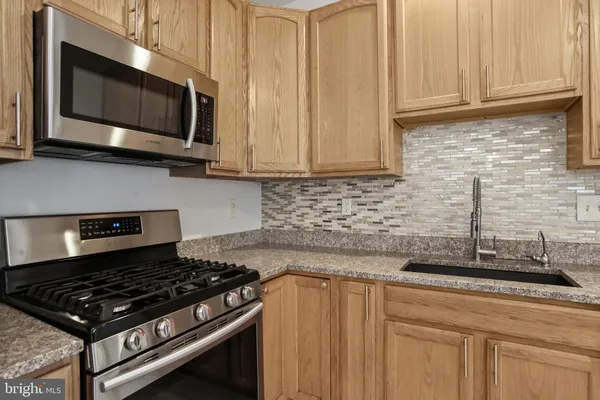 a kitchen with stainless steel appliances granite countertop a sink a stove microwave and cabinets
