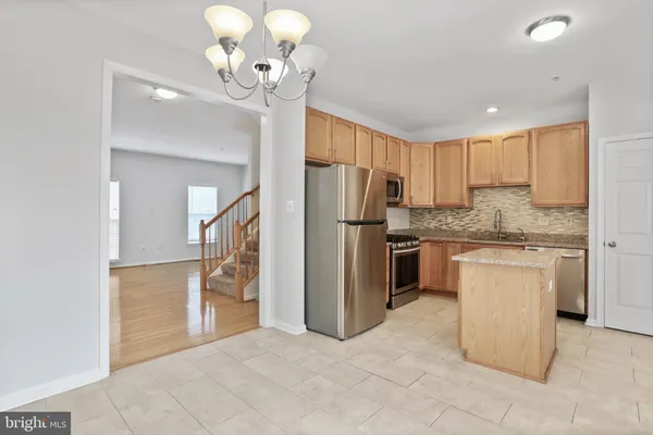 a kitchen with stainless steel appliances granite countertop a refrigerator a sink dishwasher a oven and a dining table with wooden floor