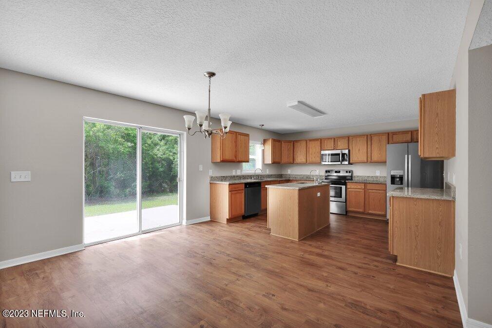 12070 Chester Creek Road Jacksonville, FL 32218 - Photo 13 of 45 a kitchen with stainless steel appliances kitchen island wooden cabinets and wooden floor
