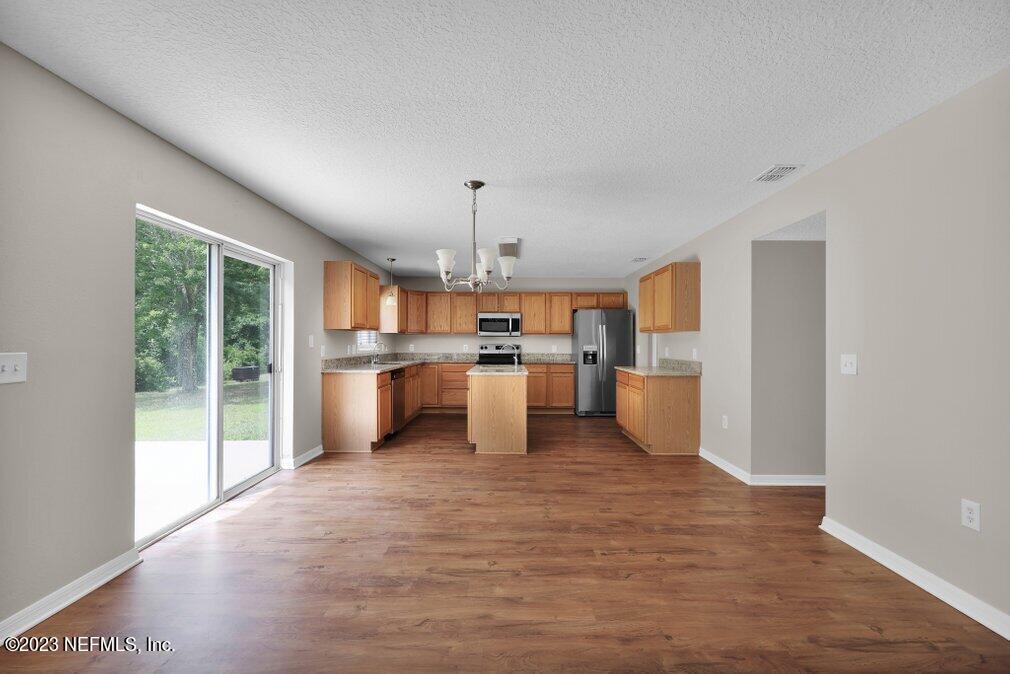 12070 Chester Creek Road Jacksonville, FL 32218 - Photo 17 of 45 a kitchen with stainless steel appliances granite countertop a stove top oven a sink dishwasher a refrigerator and white cabinets with wooden floor