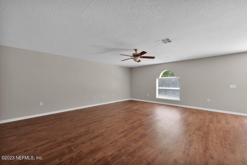 12070 Chester Creek Road Jacksonville, FL 32218 - Photo 22 of 45 an empty room with wooden floor chandelier fan and windows