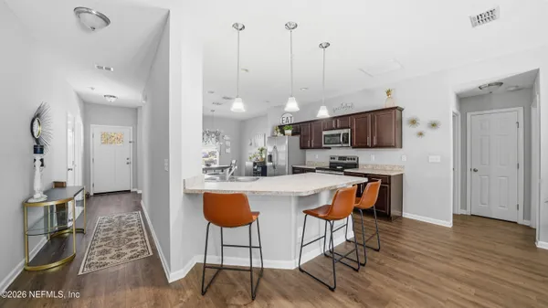 a kitchen with stainless steel appliances granite countertop a stove top oven a sink dishwasher a dining table and chairs with wooden floor