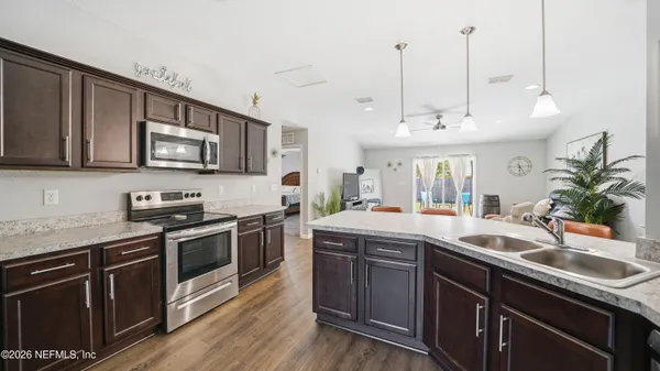 a kitchen with stainless steel appliances a dining table chairs and wooden floor
