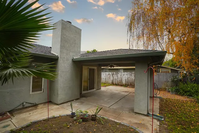 a view of a house with a small yard and floor to ceiling window and potted plants