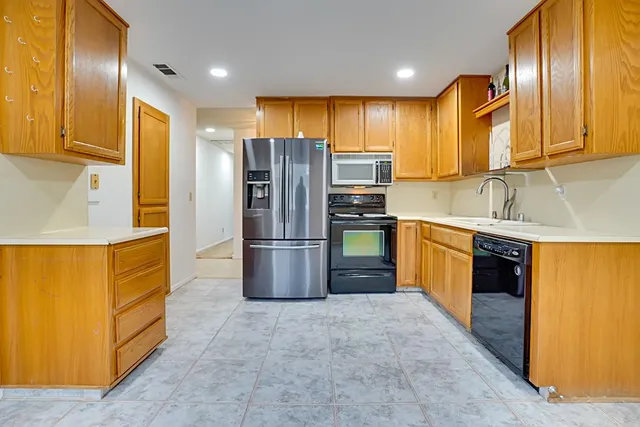 a kitchen with stainless steel appliances granite countertop a refrigerator a stove and a sink