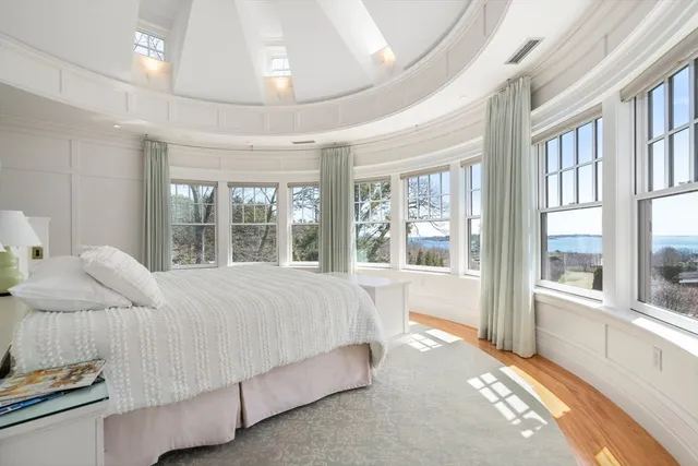 a bed sitting in a spacious bedroom next to a large window