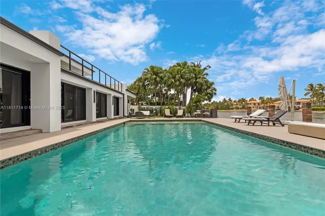 a kitchen with stainless steel appliances kitchen island granite countertop a refrigerator a stove a dining table and chairs with wooden floor