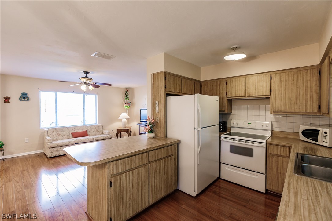 18506 Geranium Road Fort Myers, FL 33967 - Photo 13 of 32 a kitchen with a refrigerator a sink dishwasher and a stove with wooden floor