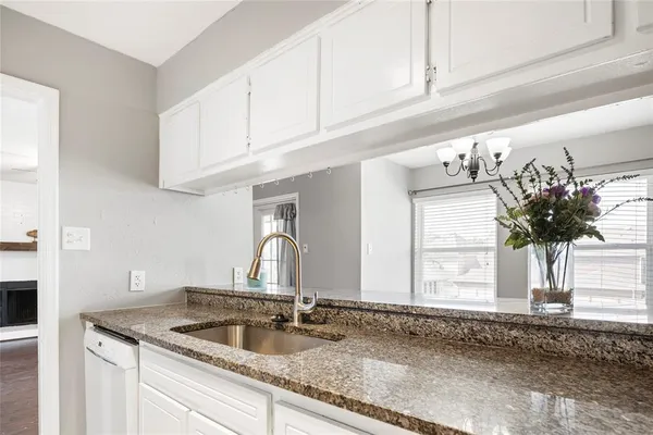 a kitchen with granite countertop a sink flowers and cabinets