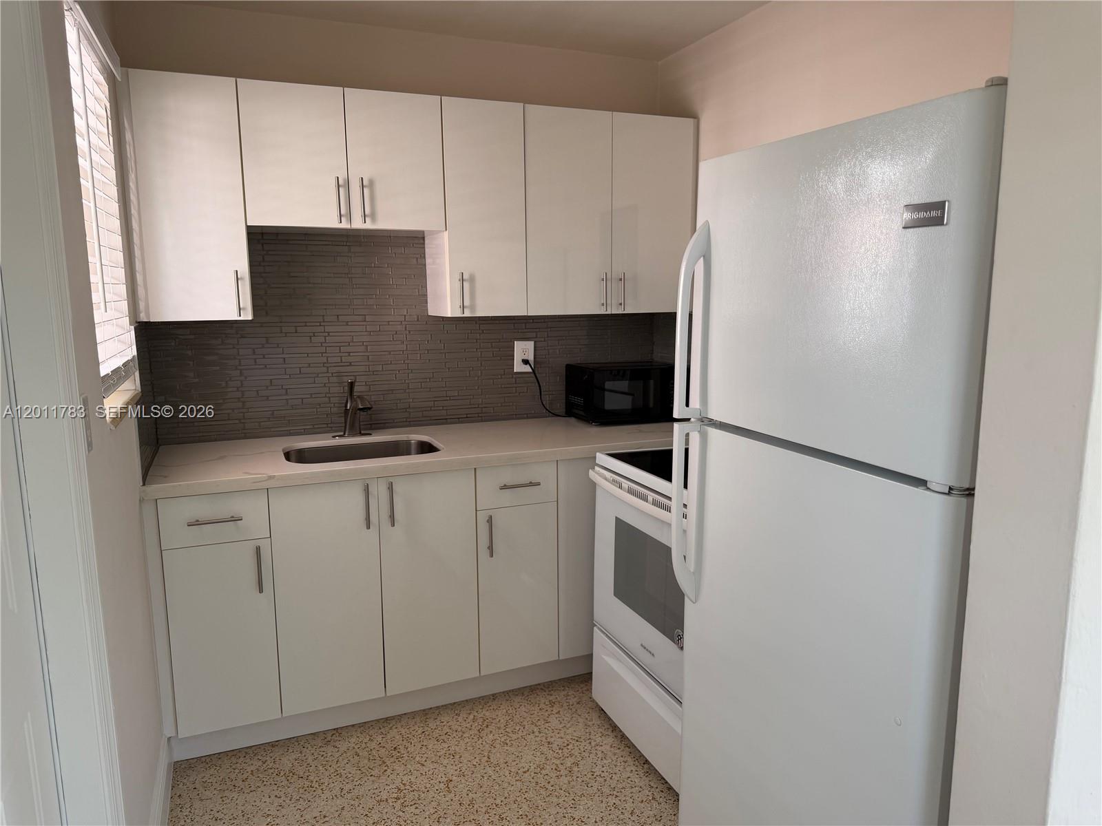 3311 Southwest 25th Terrace, Unit 3315 Miami, FL 33133 - Photo 8 of 10 a kitchen with white cabinets and white appliances