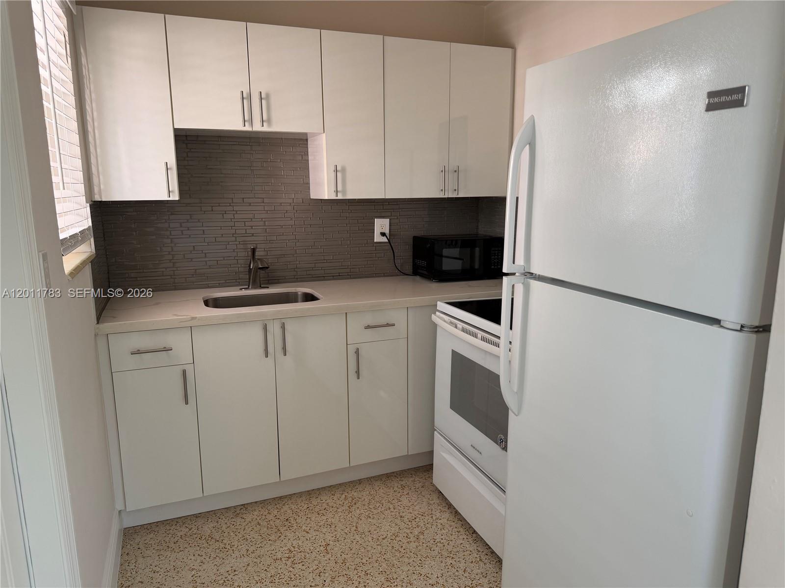3311 Southwest 25th Terrace, Unit 3315 Miami, FL 33133 - Photo 9 of 10 a kitchen with white cabinets and white appliances