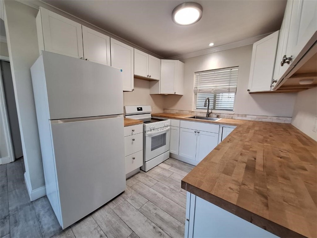 9150 44th Avenue, Unit 15 Sebastian, FL 32958 - Photo 10 of 21 a kitchen with a sink a refrigerator and white cabinets