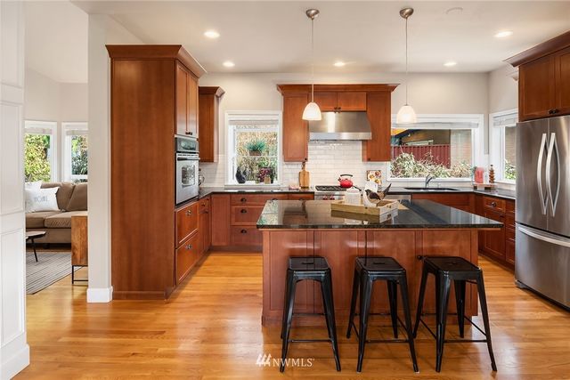 a kitchen with stainless steel appliances granite countertop a table chairs refrigerator and sink