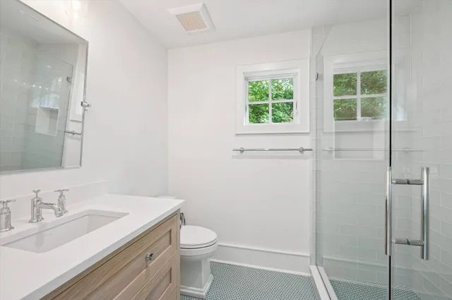 a bathroom with a granite countertop sink toilet a mirror and shower