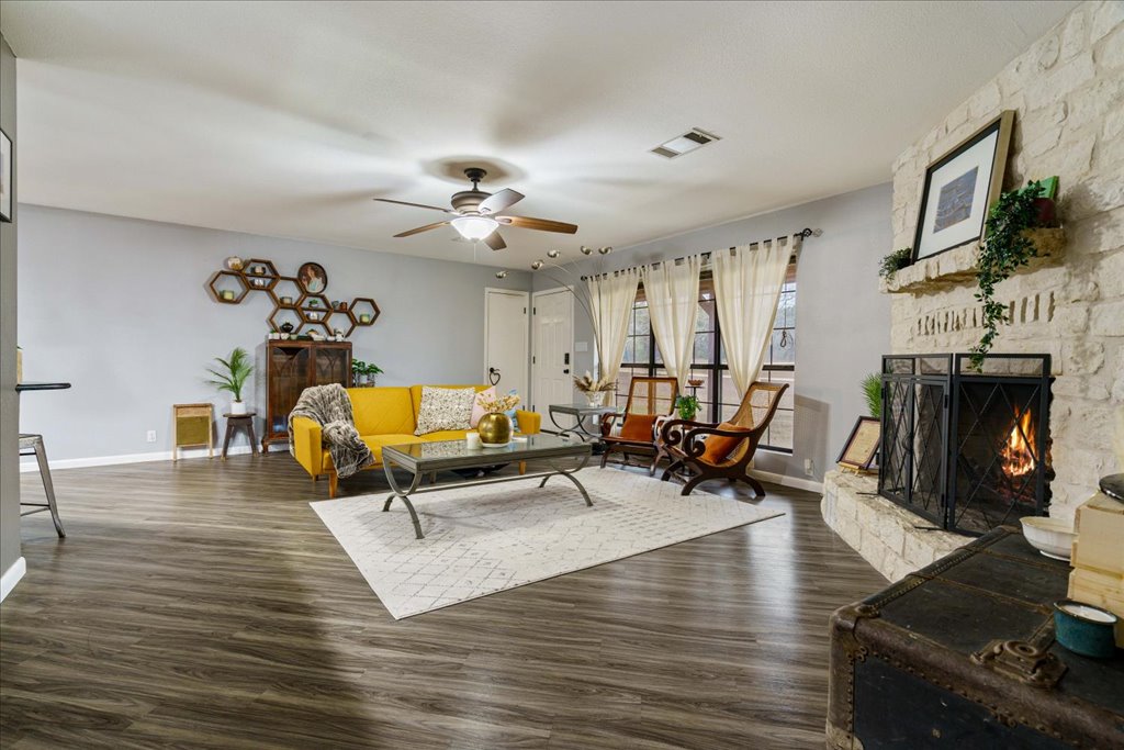 5014 Little Valley Road Leander, TX 78641 - Photo 10 of 20 A well-lit living area showcases rich wood flooring and a commanding stone fireplace, perfect for gathering.
