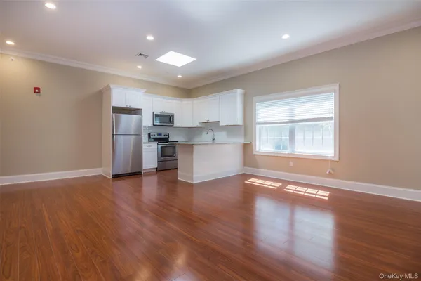 a view of a kitchen with a fridge wooden floor and a window