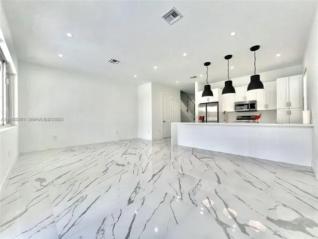a large white kitchen with kitchen island a sink stainless steel appliances and cabinets