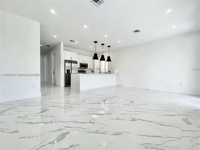 a view of large kitchen with refrigerator and window