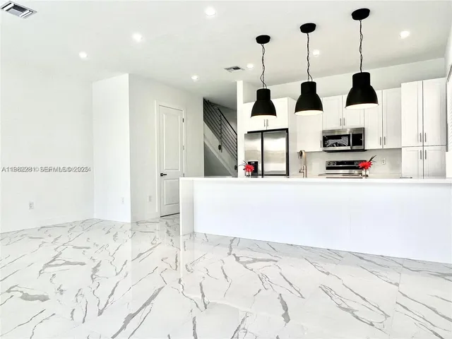 a kitchen with stainless steel appliances kitchen island granite countertop a sink and a cabinets