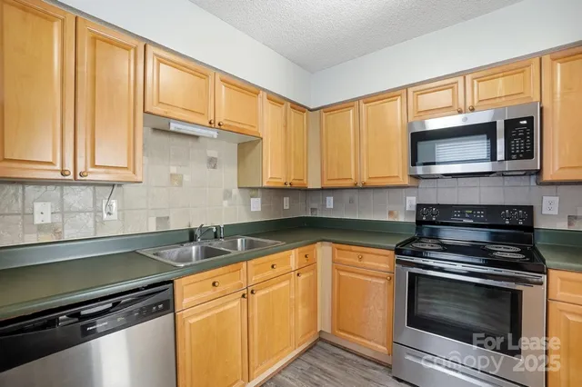 a kitchen with granite countertop cabinets stainless steel appliances and a window